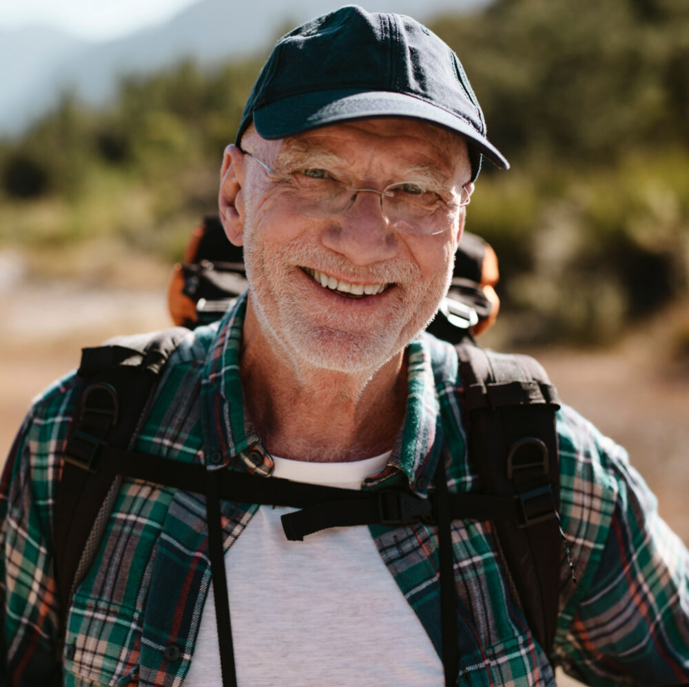 Portrait of a senior man carrying a backpack looking at camera and smiling